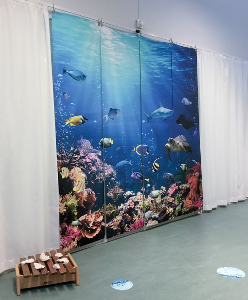 Væg med tre stofbannere, der afbilleder en eksotisk havbund med mange forskelligeartede fisk